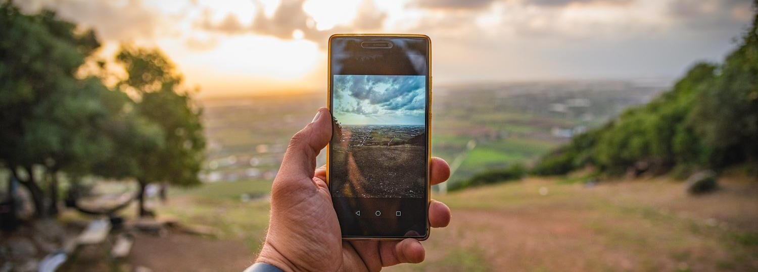 Hand holding a phone in front of landscape